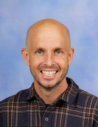 Headshot photo of teacher in front of a blue background