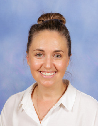 Headshot photo of teacher in front of a blue background with white shirt