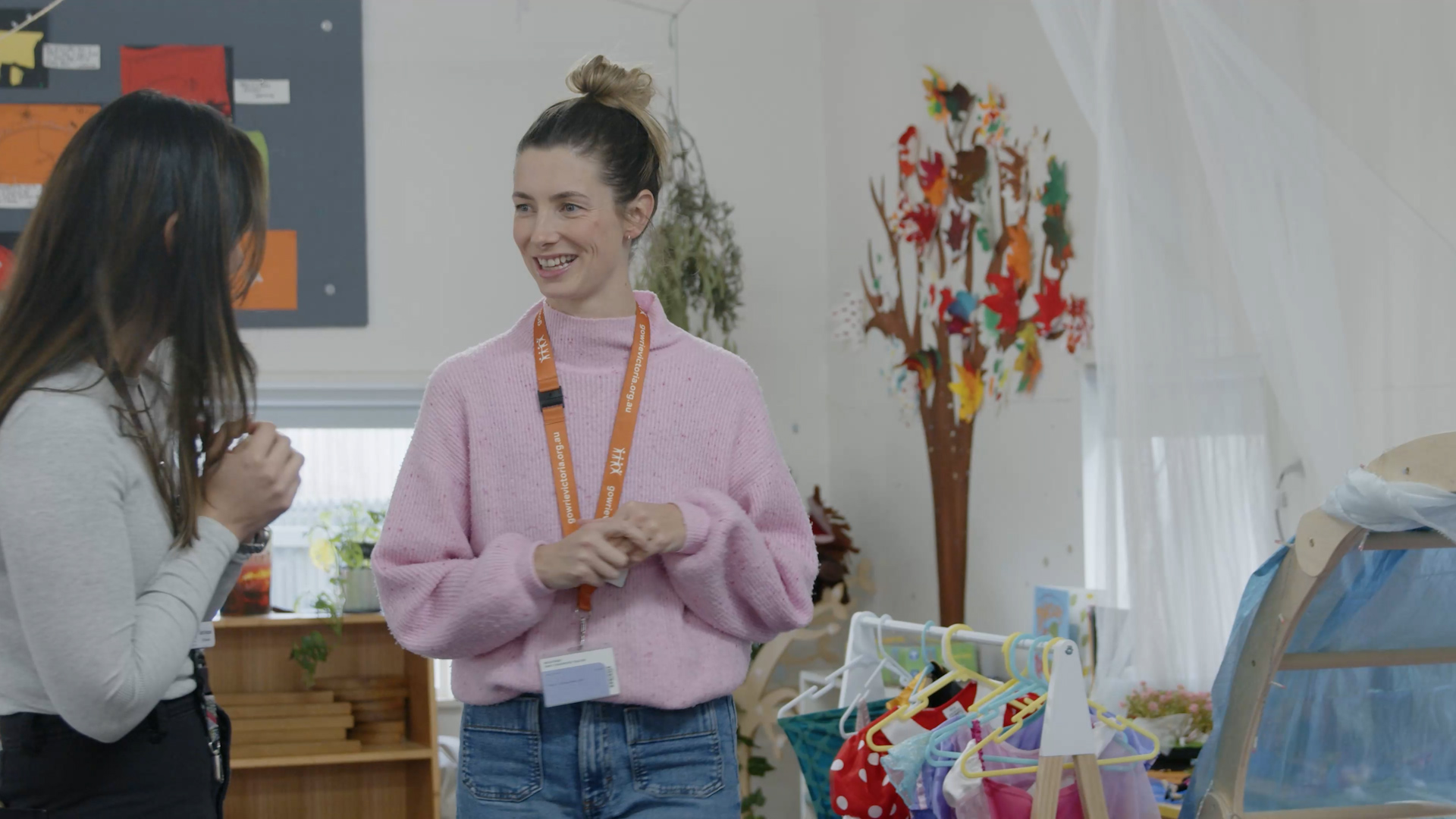Teacher in a pink jumper talking to another teacher in a white jumper