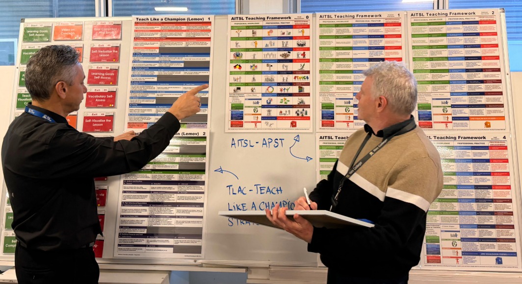 Two teachers pointing at whiteboard with print outs for training