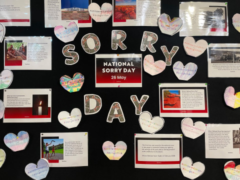 Image of a board with letters that spell "sorry day". Around the letters are images and text.