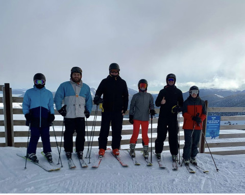 Teacher and students, standing on the snow, wearing snow gear and skis