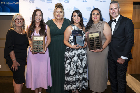 Team smiling at the camera, holding an award
